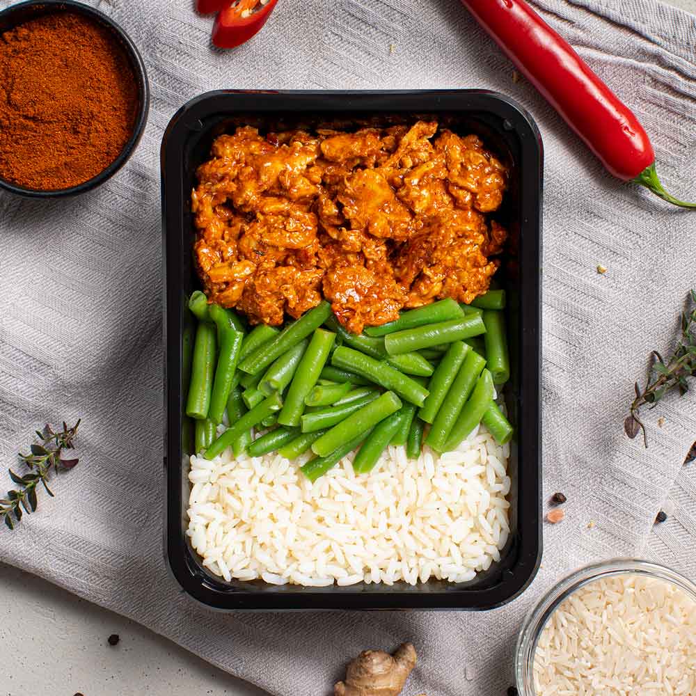 Gezonde kant-en-klare mealprep maaltijd met pittige kip rijst en boontjes voor droogtrainen