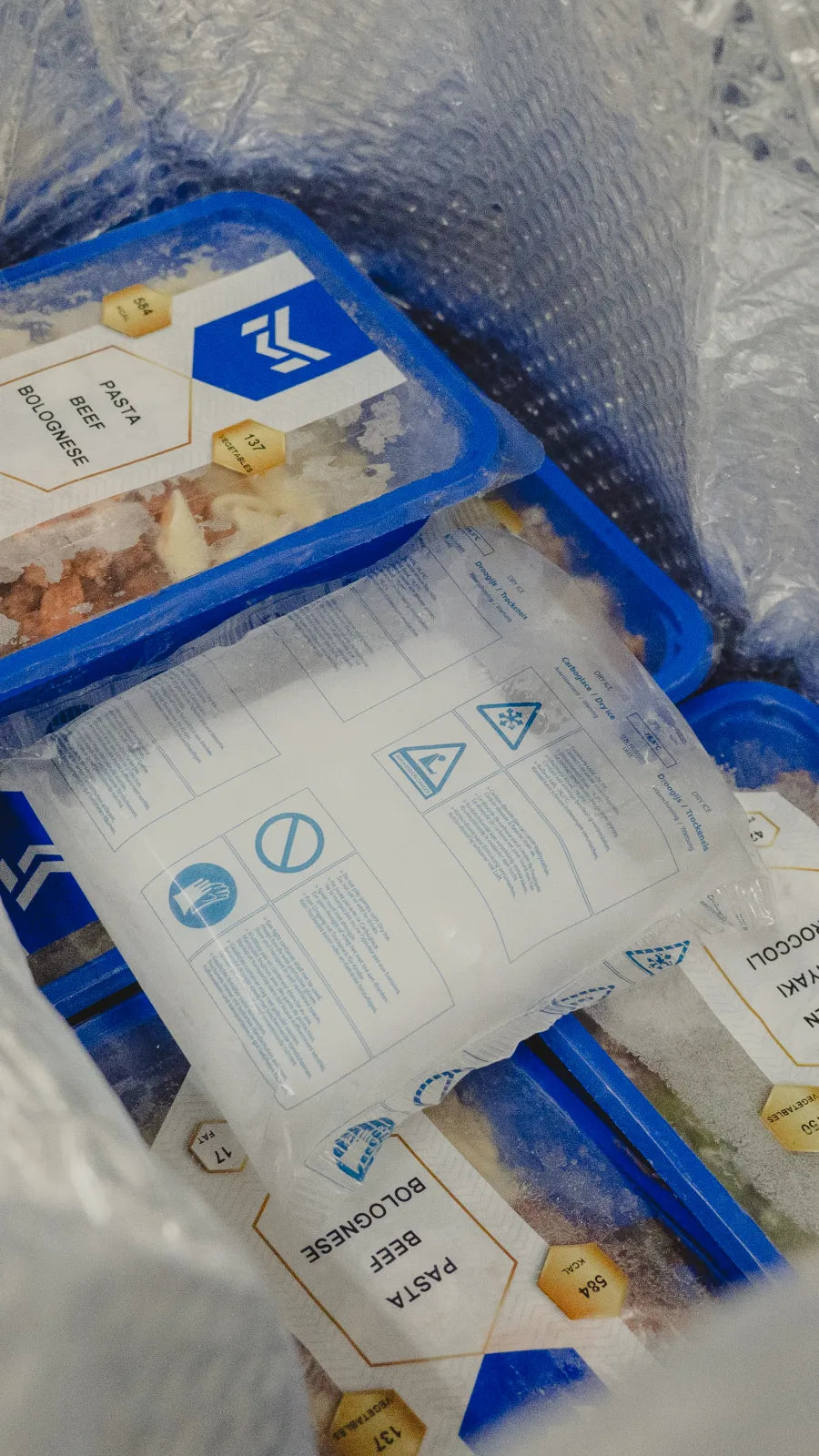 Bevroren SportMeals-bakjes met een zak droogijs in de isolatiezak