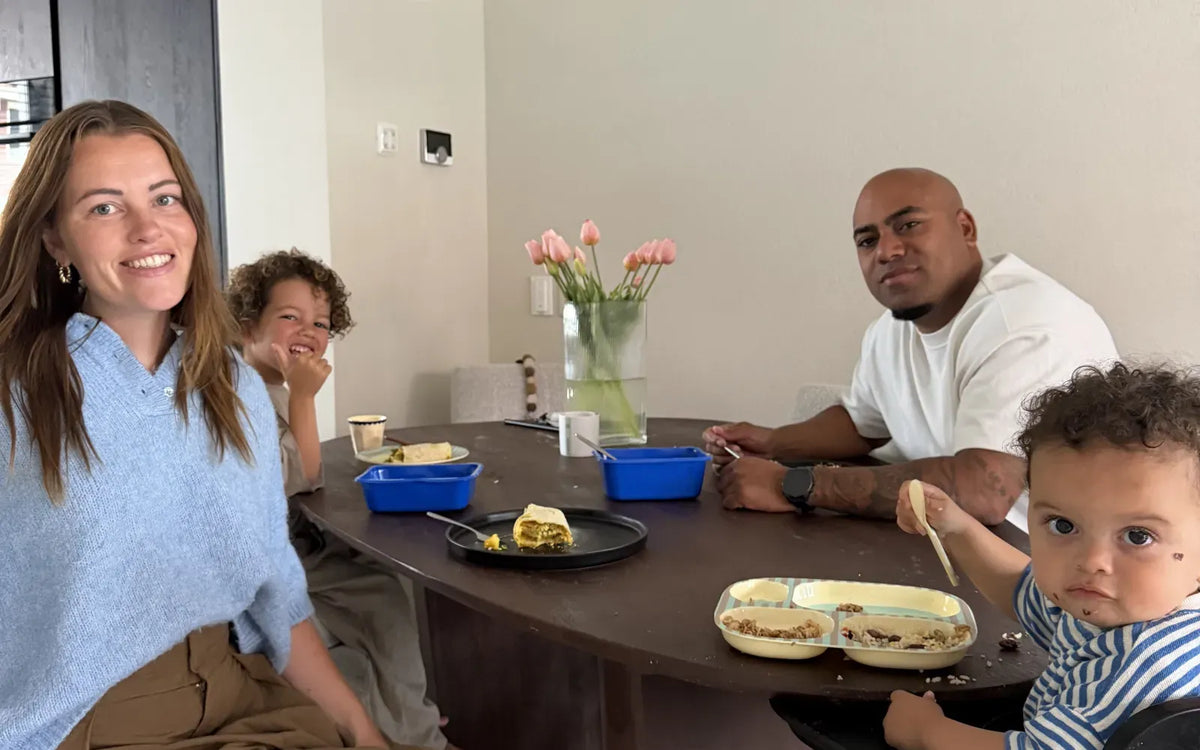 A family with two young children at the dining table, with blue SportMeals meals and plates on the table