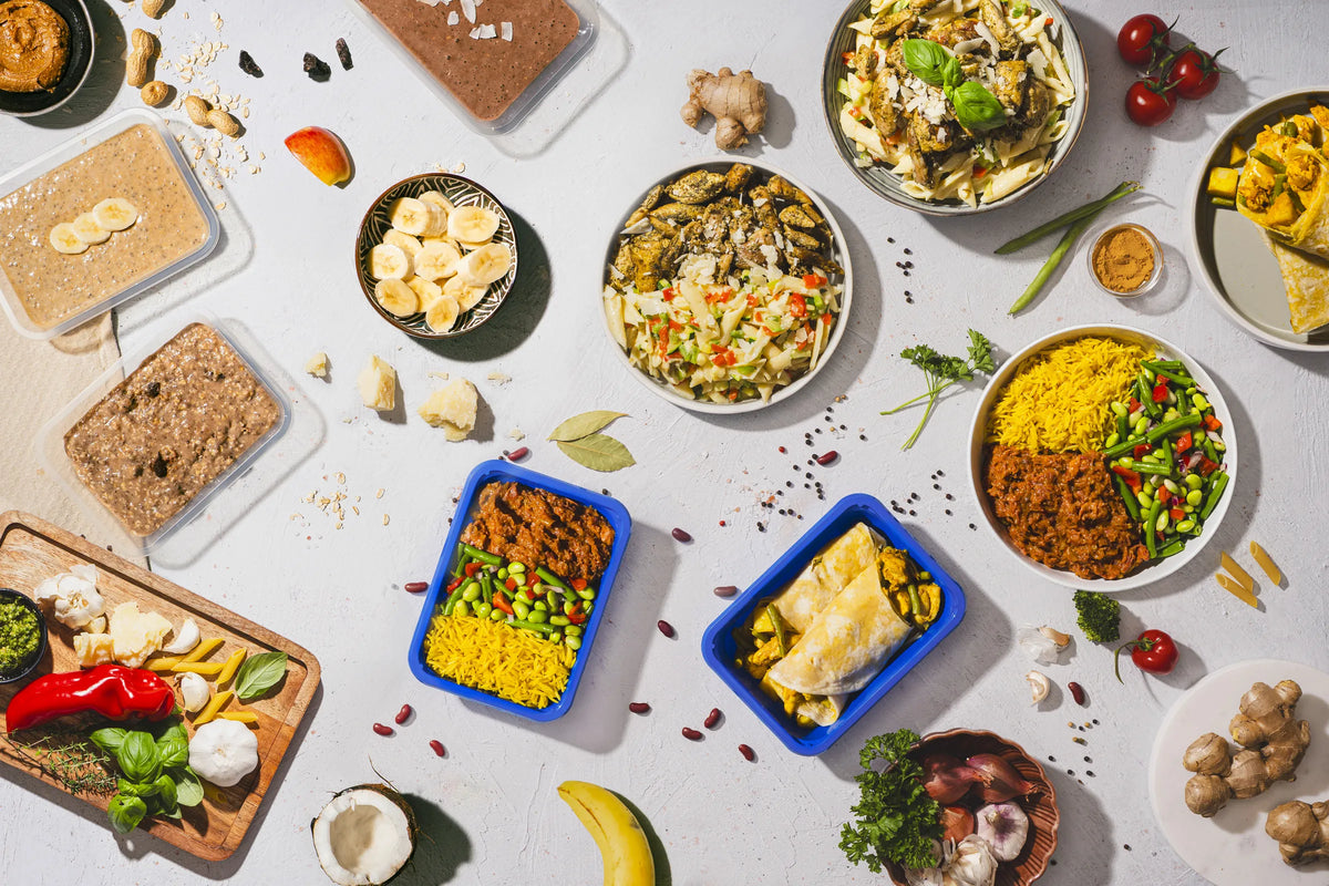 Bovenaanzicht van SportMeals-maaltijden, overnight oats en een wrap op een lichte tafel