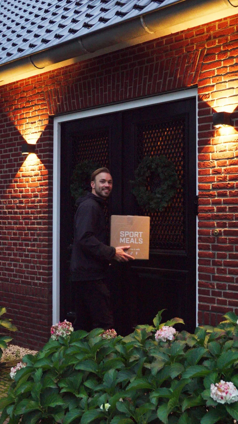 Bezorger met een gesloten SportMeals-doos aan de voordeur