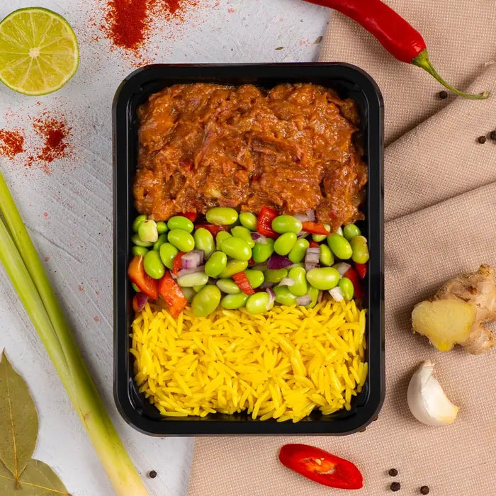 Beef rendang met gele rijst en edamame in een bakje